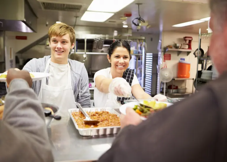 Ein Mann und eine Frau geben Essen in einer Kantine aus.