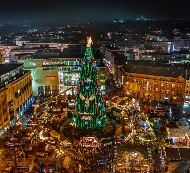 Ein Blick von oben auf die erleuchtete Dortmunder Weihnachtsstadt bei Nacht, im Zentrum steht der Weihnachtsbaum.