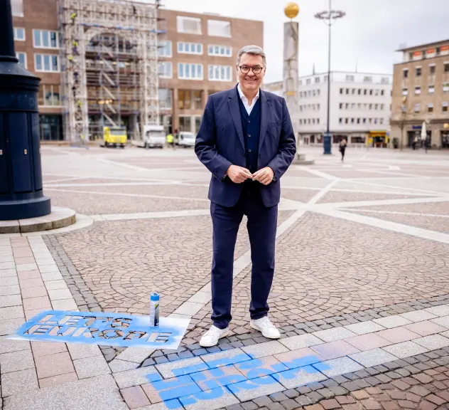 Zu sehen ist Oberbürgermeister Thomas Westphal. Vor ihm wurde mit einer Schablone der Satz „Let’s Europe“ auf dem Friedensplatz gesprüht.