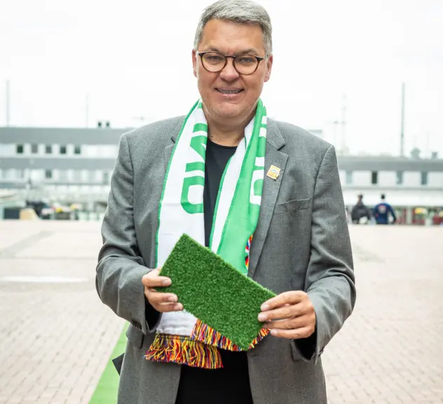 Oberbürgermeister Thomas Westphal hält ein Stück vom grünen Teppich in den Händen