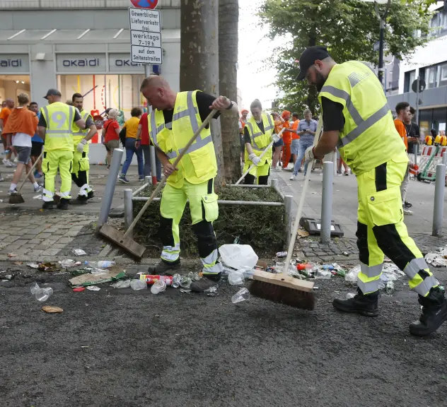 Zwei Mitarbeiter der EDG fegen in der Fußgängerzone Müll zusammen.