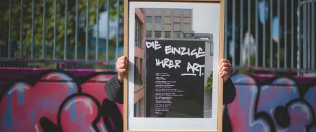 Eine Person hält den Kunstdruck in einem Holzrahmen in den Händen