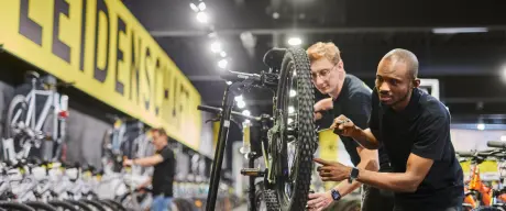 Zwei Menschen bauen in einem Fahrradgeschäft ein Fahrrad zusammen/reparieren es