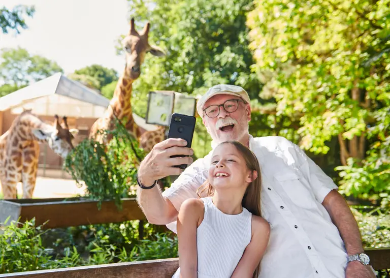 Opa und Enkelin schießen ein Selfie vor den Giraffen im Dortmunder Zoo