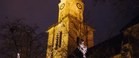 Die Reinoldikirche bei Nacht, im Vordergrund sind kahle Bäume mit Lichterketten geschmückt