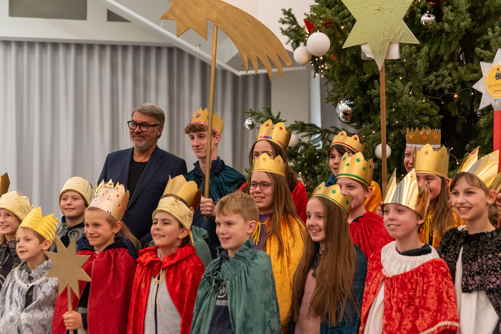 Oberbürgermeister Thomas Westphal steht gemeinsam mit vielen Kindern und Jugendlichen im Rathaus. Diese sind als Heilige drei Könige verkleidet.