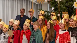 Oberbürgermeister Thomas Westphal steht gemeinsam mit vielen Kindern und Jugendlichen im Rathaus. Diese sind als Heilige drei Könige verkleidet.