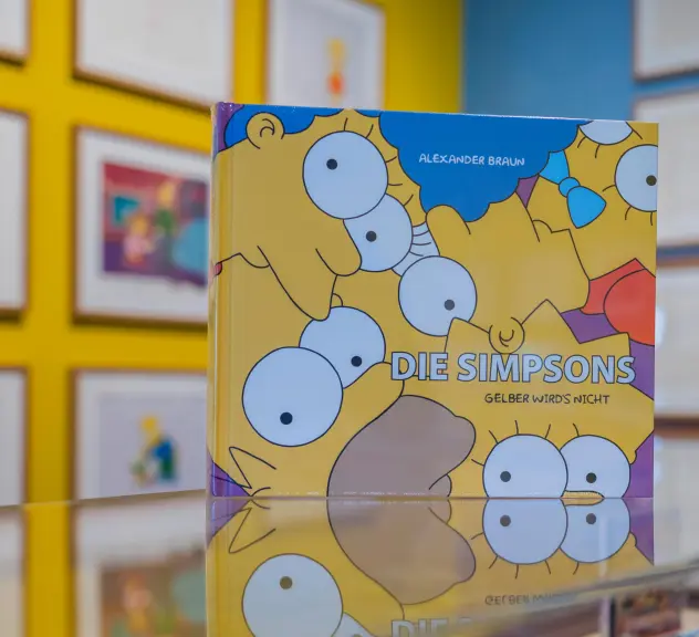 Simpsonsausstellungsbuch auf einem Glastresen im Ausstellungsraum