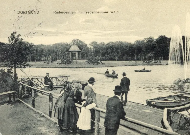 Antike Postkarte mit Menschen vor einem See mit Wasserfontäne im Park