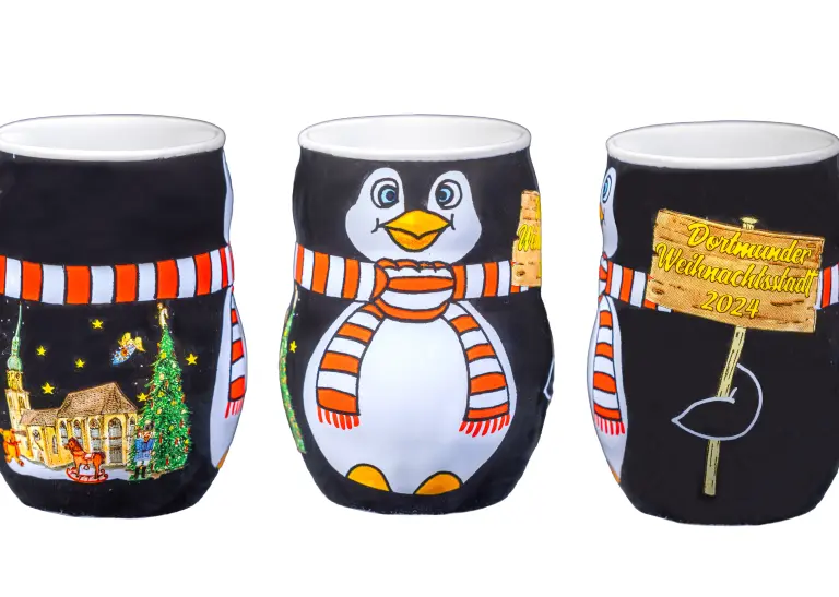 Glühweintasse des Dortmunder Weihnachtsmarktes 2024: Eine schwarze Tasse mit Pinguin-Aufdruck und einer Kirche. 