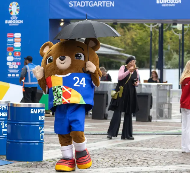 EURO 2024-Maskottchen Albärt mit Regenschirm an der Fan Zone Friedensplatz.