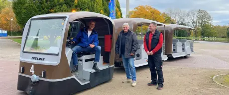 Drei Männer stehen nebeneinander vor der neuen solarbetriebenen Parkbahn im Westfalenpark Dortmund. Links steht Marc Büchsenschütz vom Westfalenpark, in der Mitte Peter Amberg und rechts Mike Weidling, beide von der Firma Intamin. Die Männer lächeln und präsentieren stolz die moderne Parkbahn.