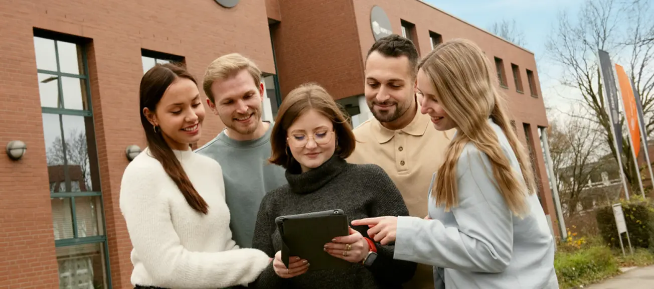 Eine Gruppe von jungen Menschen, welche sich zusammen auf dem Ipad etwas anschauen 