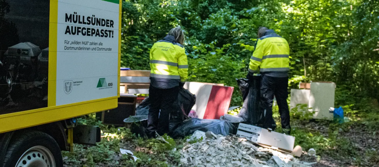 Zwei Männer, welche gerade dabei sind in einem Waldstück Müll aufzusammeln