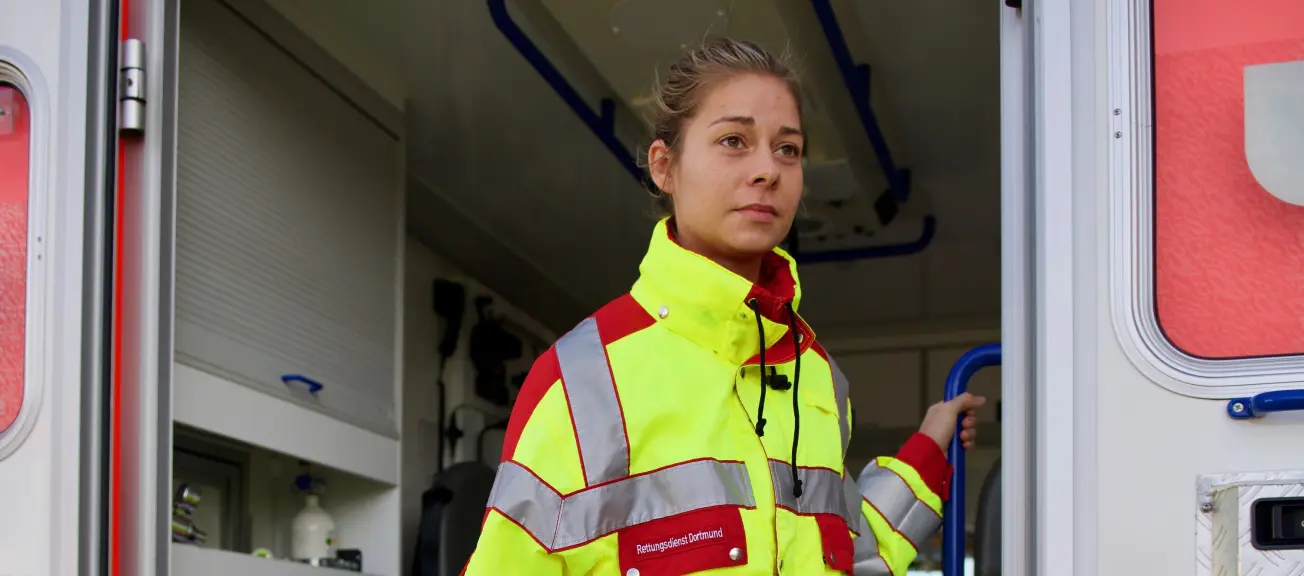 Eine Notfallsanitäterin, welche gerade aus dem Rettungswaagen steigt 