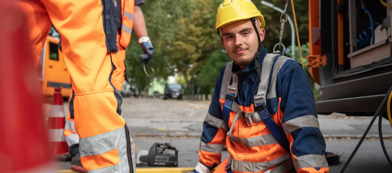 Ein Mann, welcher in die Tiefe hinab gelassen wird und nett in die Kamera lächelt