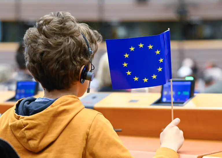 Junge hält kleine Europaflagge im Europäischen Parlament