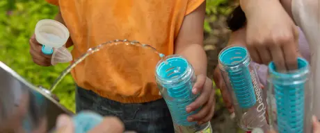 Kinder füllen ihre Flaschen am Trinkwasserbrunnen auf