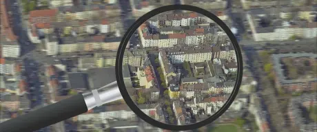 Fotomontage eines Luftbilds einer Siedlung mit einer großen Lupe darüber