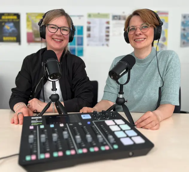 Jennifer Beck und Katharina Rudolphi mit Kopfhörern und technischem Equipment beim Podcasten