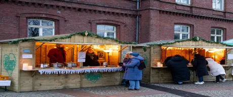 Menschen vor den Holzhütten vom "Winterzauber Borsigplatz" Weihnachtsmarkt