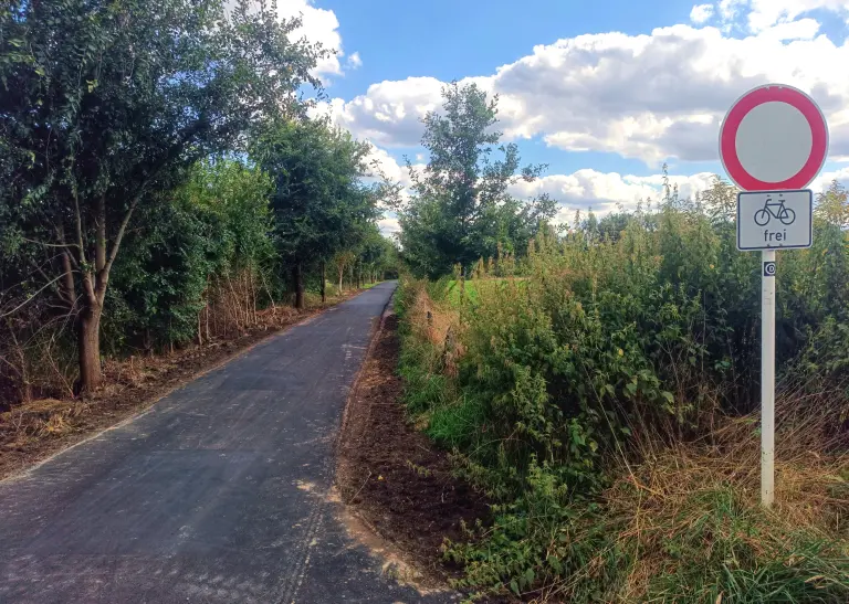 Neuasphaltierter Weg im ländlichen Bereich von Mengede zwischen der Straße Königsheide und der Halde Minister Achenbach. Rechts im Bild steht ein Schildermast mit dem Verkehrszeichen 250 / Durchfahrt verboten. Darunter ist der Zusatzzeichen 1022-10 / Fahrrad frei zu sehen.