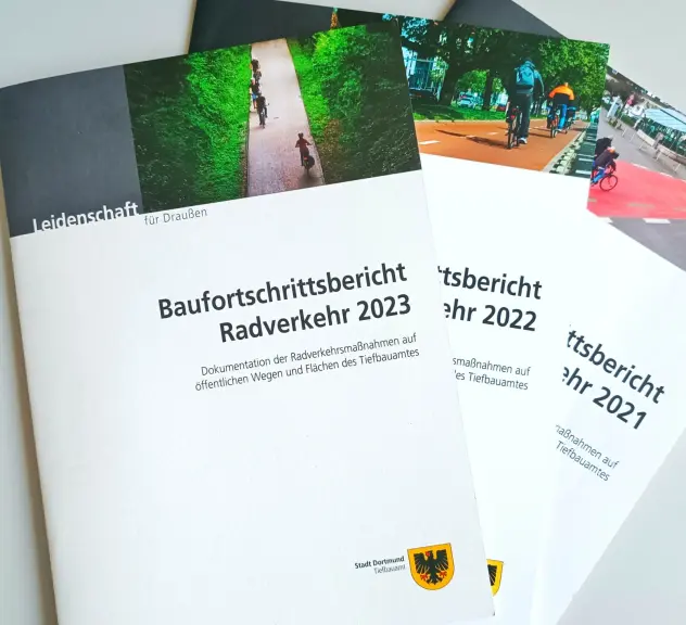 Baufortschrittsberichte Radverkehr 2021 bis 2023 liegen gefächert auf einem Tisch.