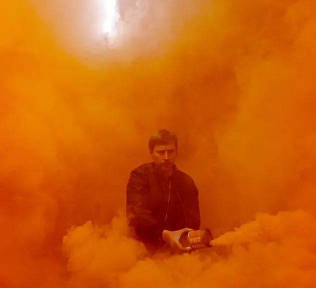 Ein Mann steht in orangenem Nebel