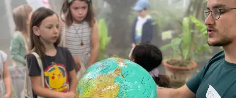 Kinder stehen um einen Mann mit einem Globus in der Hand