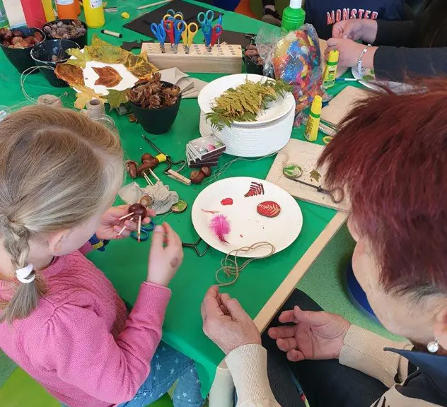 Kastanien, Blätter und andere Materialien liegen zum Basteln auf einem Tisch