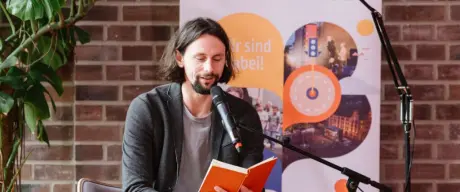 Es ist zu sehen wie Neven Subotić das Buch „Voll ungerecht. Über Fairness und Gerechtigkeit“ liest