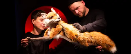 Zwei Schauspieler und eine Puppe in Form eines Fuchses