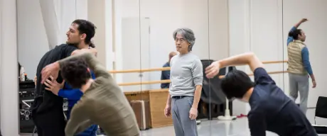 Tänzer stehen um den Choreografen in einem Ballettsaal