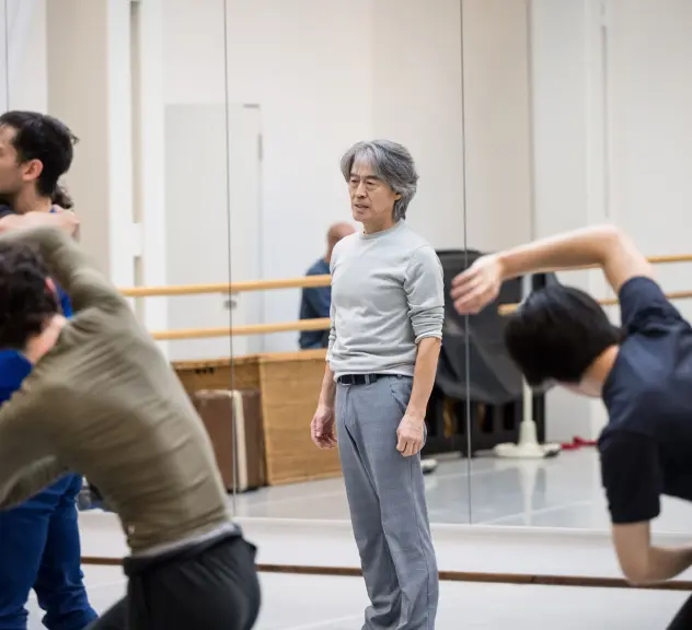 Tänzer stehen um den Choreografen in einem Ballettsaal