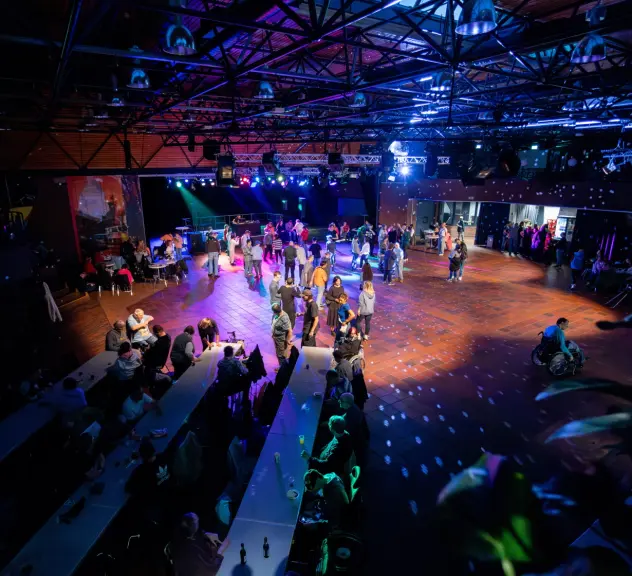 Ein Überblick über die Disco im Keuninghaus. Menschen tanzen bei buntem Licht.