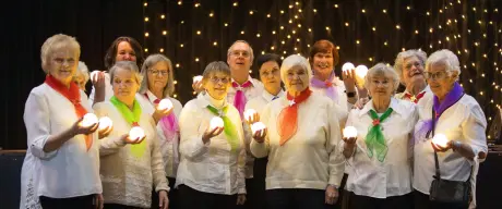 Ein Foto des Chors in weißer Kleidung, bunten Tüchern und Lichtern bekleidet