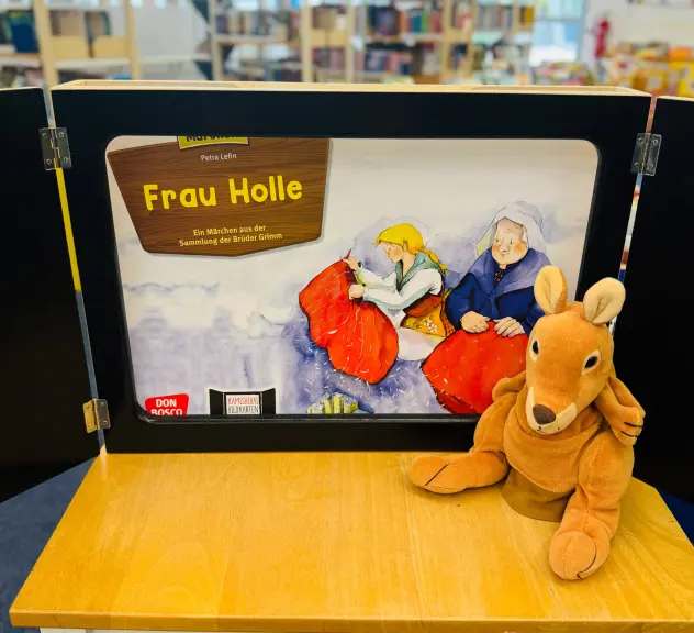 Ein Bild zur Geschichte sowie ein Känguru-Stofftier auf einem Tisch in der Bibliothek