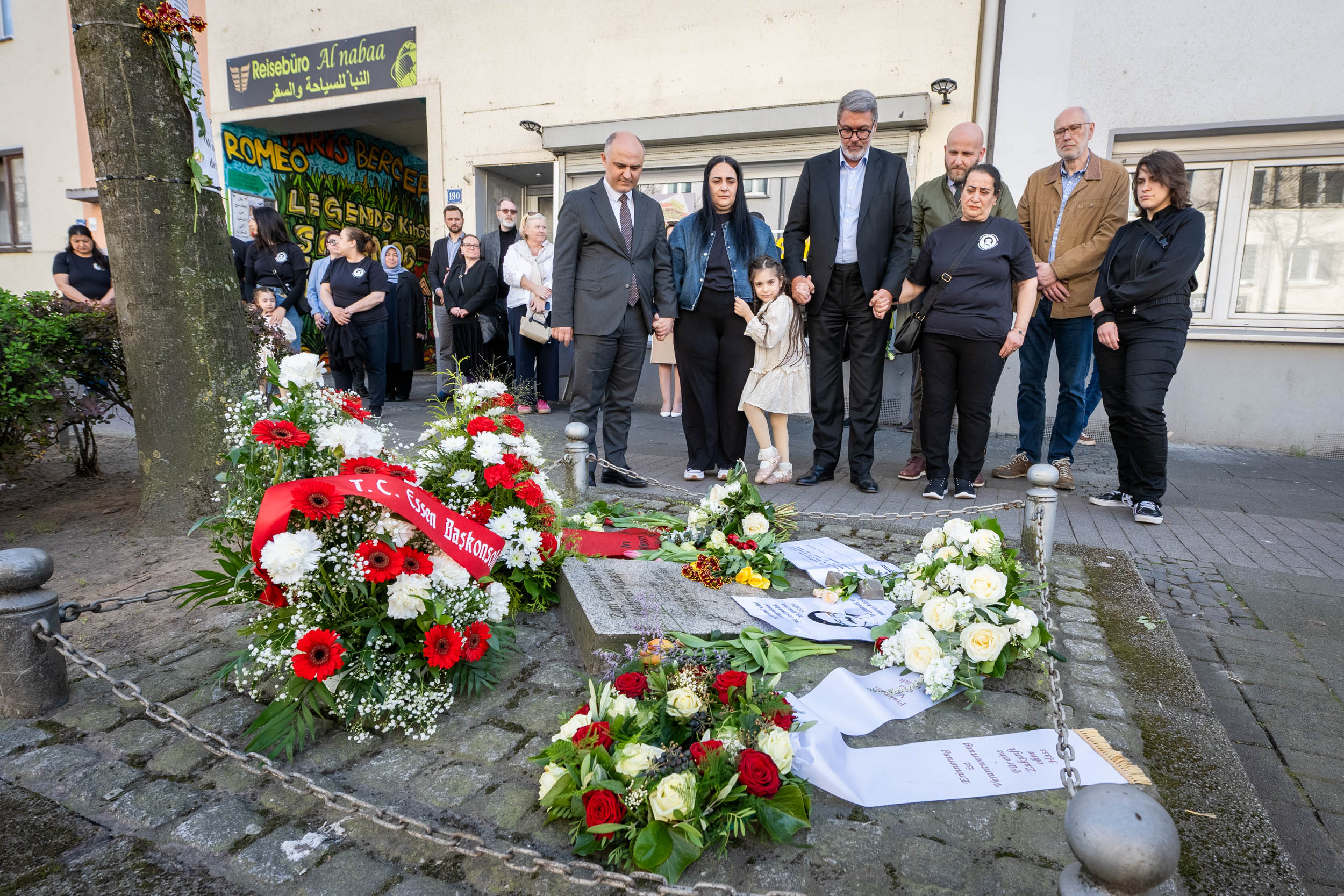 Menschen in Andacht an einem Gedenkstein.