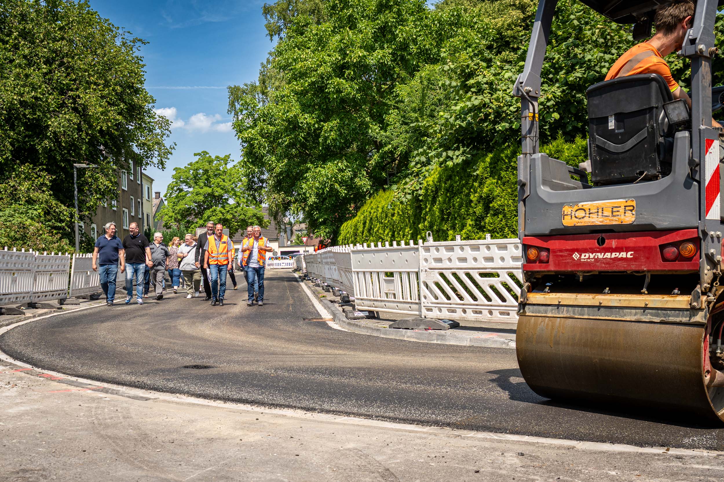 Eine Gruppe geht über eine Straße, die abgesperrt und saniert wird.